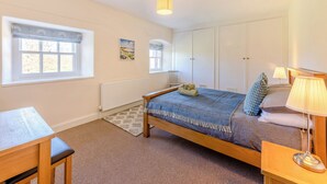 A bedroom with a bed, bedside table, lamp, window with blinds, radiator, and a painting on the wall. - The Old Bakery - UK48319 (Berwick-Upon-Tweed)