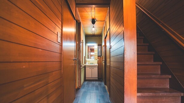 Un couloir en bois avec un escalier sur la droite.