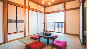 Perinteinen japanilainen huone, jossa on tatamimatto, matala pöytä teekupit ja -astiasto sekä shoji-paperi-ikkunat.