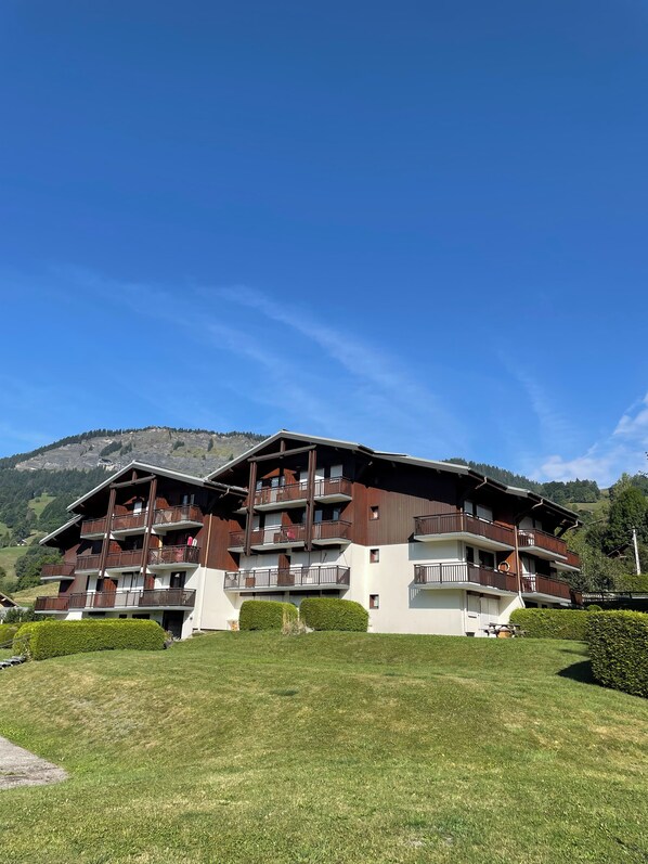Un hôtel à plusieurs étages, doté de balcons, situé dans un cadre montagneux.