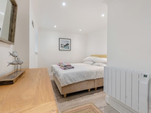 A bedroom with a bed, bedside table, and a radiator.