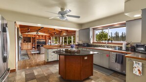 A modern kitchen with a central island, wooden cabinetry, and a large window providing a view of the outdoors. - Rainier Ranch & Poolside Escape (Enumclaw)