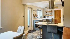 A modern kitchen with a central island, bar stools, and a dining table.