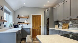 A modern kitchen with grey cabinets, a large island, and a wooden door.