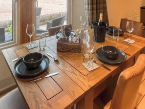 A dining table set with black plates, cutlery, and wine glasses, with a bottle of champagne and a pitcher on the table. - Stewards Bothy - UK48303 (Berwick-upon-Tweed)