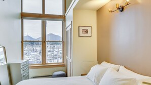 A hotel room with a large window, a bed, a dresser, and a wall-mounted light fixture. - Custom Harborside Loft In the Heart of Ketchikan (Ketchikan)