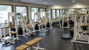 A gym with various exercise machines, benches, and a large exercise ball.