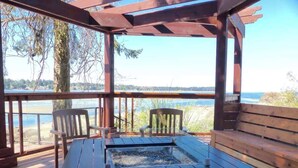 A wooden deck with a table and chairs, overlooking a body of water.