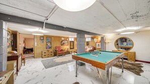 Une pièce avec une table de billard, des meubles en bois et un miroir au mur.
