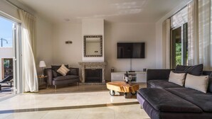 A spacious living room with a fireplace, a large flat-screen TV, and a comfortable seating area. - Casa Rosa - Heated Pool & Sea Views (Loulé)
