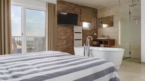 A hotel room with a large bed, a bathtub, a TV, and a balcony with a view. - Casa Rosa - Heated Pool & Sea Views (Loulé)