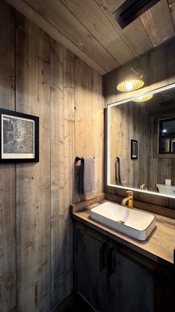 A wooden bathroom with a sink, mirror, and towel rack.