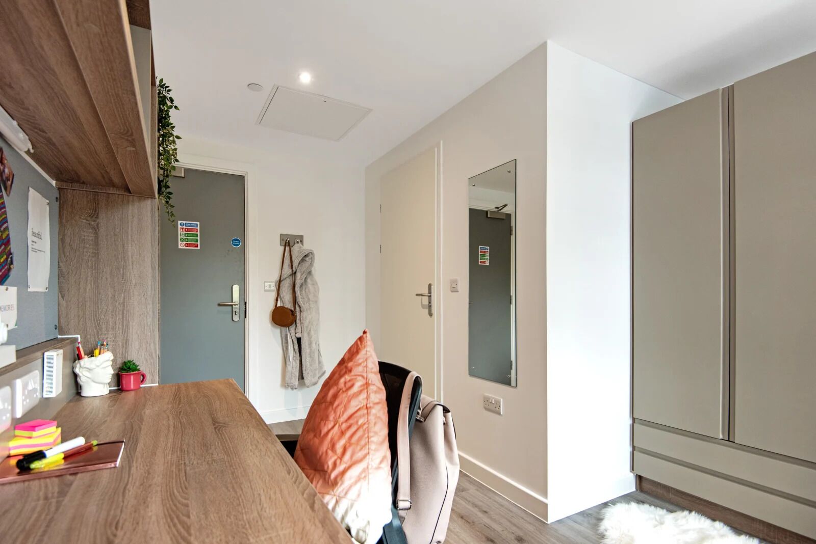 A modern room with a wooden dining table, a large mirror, and a wardrobe.