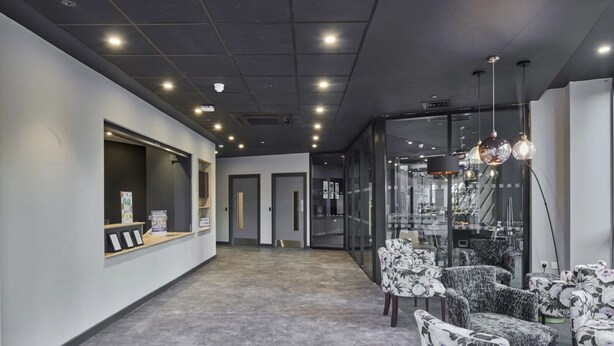 Un interno moderno con reception, area salotto e pareti divisorie in vetro.