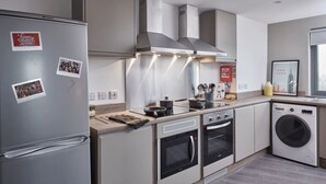 Una cucina moderna con forno integrato, microonde e una lavatrice e asciugatrice a spazio ridotto.