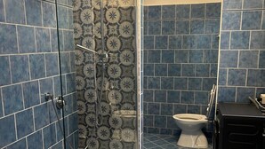 A bathroom with blue tiles, a glass-enclosed shower, a toilet, and a sink. - Optima mansio (Roma)