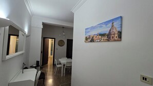 A hallway with a dining area, a clock, and a painting of a building. - Optima mansio (Roma)