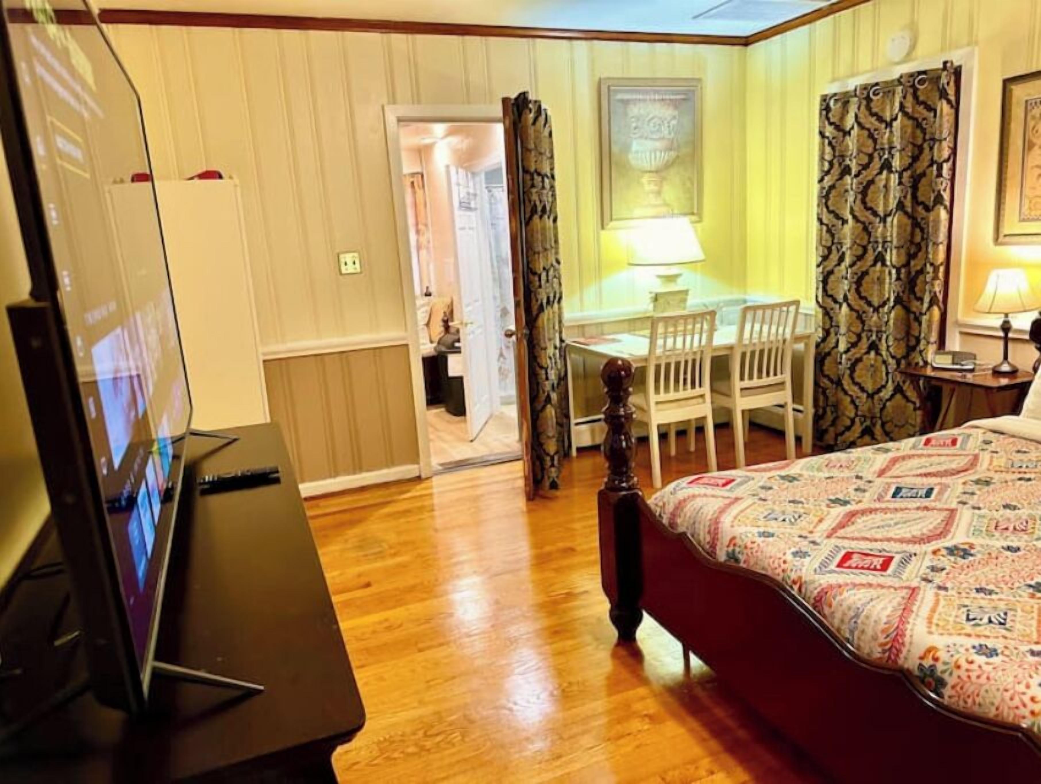 A hotel room with a bed, a desk with a chair, a television, and a lamp.