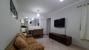 Een woonkamer met een bank, televisie en een eethoek.