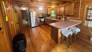 A wooden cabin kitchen with a central island, stainless steel appliances, and wooden cabinets.