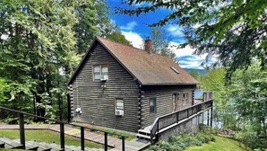 A log cabin with a wooden deck and a small staircase leading to the entrance.