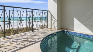 A balcony with a view of the beach and a swimming pool.