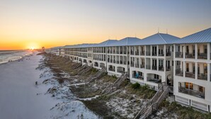 A beachfront hotel with multiple balconies, a beach view, and a sunset.