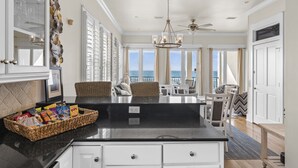 A spacious kitchen with a large island, white cabinetry, and a view of the ocean.