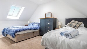 Ein Schlafzimmer mit zwei Betten, einem Schminktisch, einem Oberlicht und einem Nachttisch.
