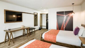 A hotel room with two beds, a desk, a mirror, and a wardrobe.