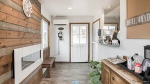 A hallway with wooden paneling, a bench, a door, and a coffee station.