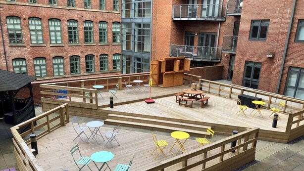 An outdoor deck with multiple seating areas, including tables and chairs, surrounded by a wooden fence. - Corner House in Sheffield (Sheffield)