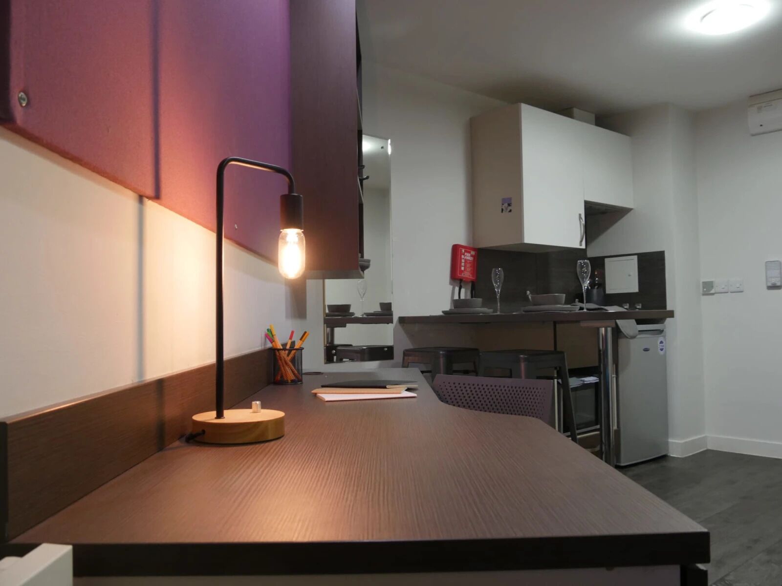 A modern kitchen with a dark wooden countertop, a pendant light, and a small table with a cup holder.