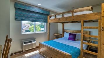 Une chambre avec un lit superposé, une fenêtre, un radiateur et une vue sur une maison.