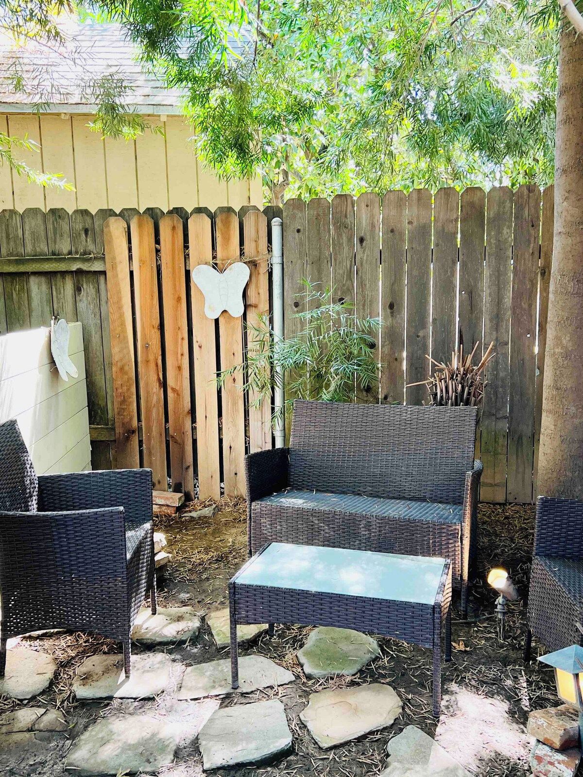 A patio area with wicker furniture, a stone table, and a wooden fence with a butterfly decoration.