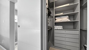 Un dressing avec des étagères, des tiroirs et un espace pour suspendre les vêtements, le tout dans des tons de gris.