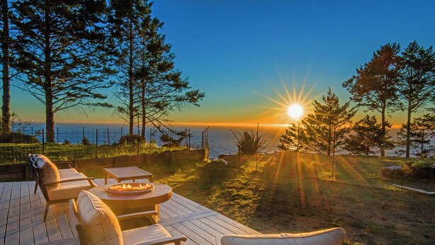 A deck with outdoor seating and a fire pit, overlooking a body of water and trees. -  Overlooking the ocean, sleeps 7, kid and pet friendly, pergola with privacy. (Whitethorn)