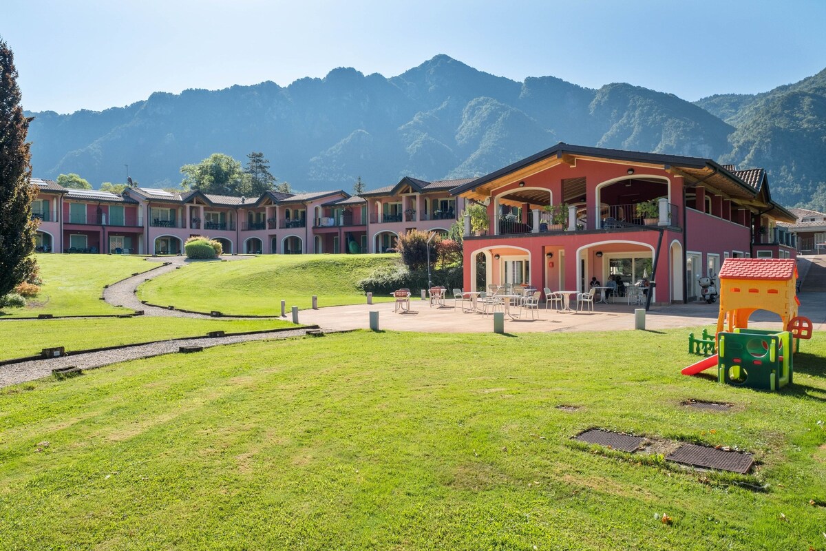 A hotel with multiple buildings, a playground, and a mountain backdrop.