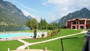 A hotel with a swimming pool, a tennis court, and a mountain backdrop. - Spacious Apartment in Idro With Shared Pool (Idro)