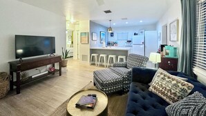 Una sala de estar moderna con televisor de pantalla plana, un sofá, una mesita de centro y un ventilador de techo.