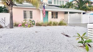 Una casa de un nivel con un porche cubierto, una bandera y un camino de entrada de grava.