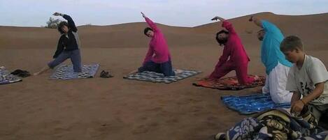 A group of people performing yoga in a desert setting.