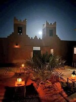 Un edificio tradicional con dos torres y un patio con palmeras y faroles.