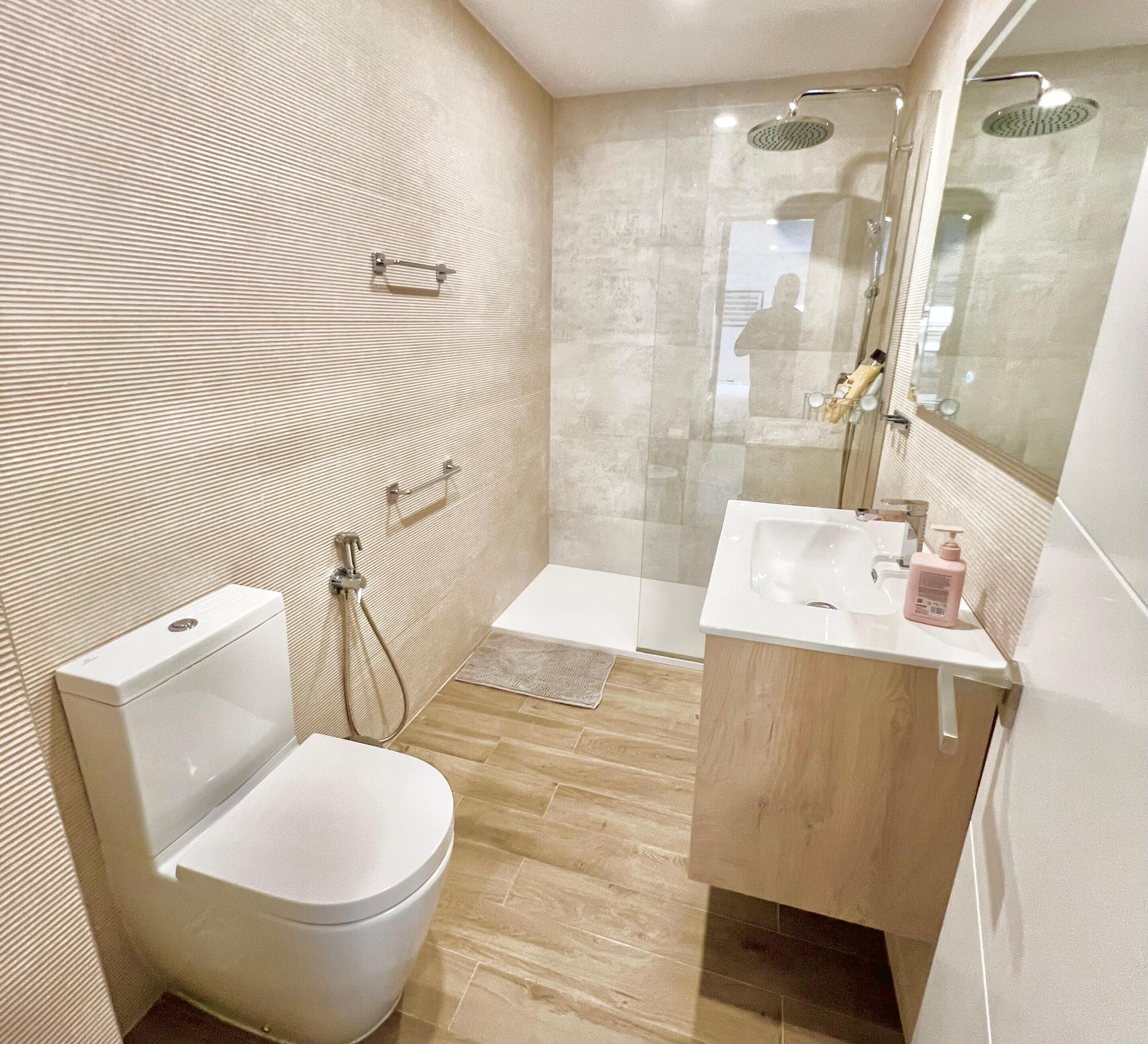 Een moderne badkamer met toilet, wastafel en douche.