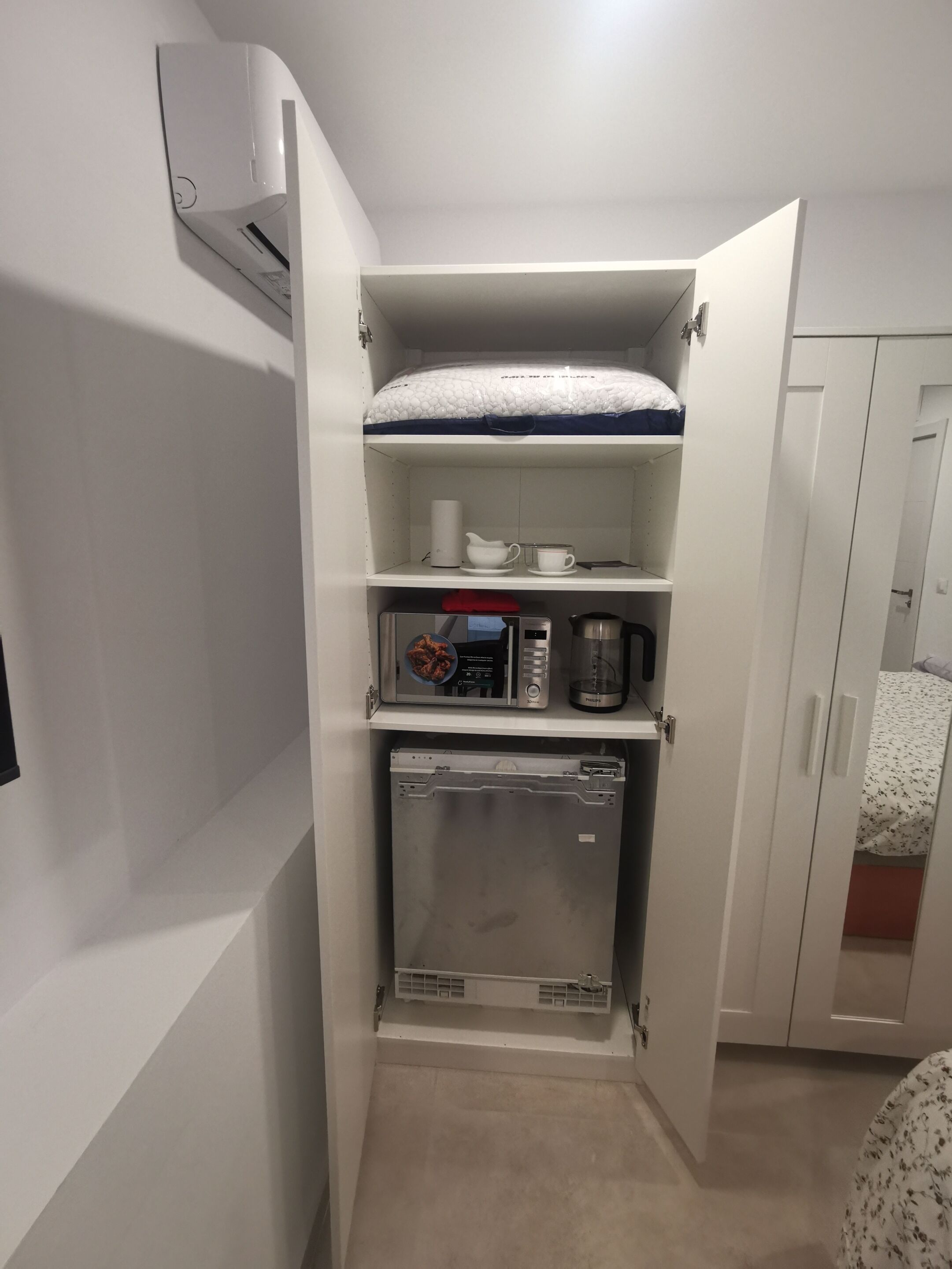 A compact kitchenette with a microwave, coffee maker, and a small refrigerator.
