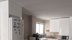 Una cocina moderna con armarios blancos, horno integrado y microondas.