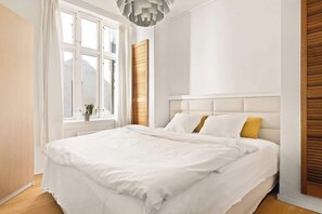 Relax in this serene bedroom with a large bed and natural light pouring in through the window.