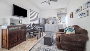 A modern living room with a brown sofa, a wooden cabinet, a flat-screen TV, and a ceiling fan. - Cozy 2-bedroom apartment with AC, WiFi in charming Cabo San Lucas (Cabo San Lucas)