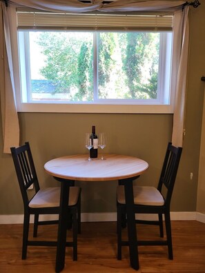 A dining area with a round table, two chairs, a bottle of wine, and two wine glasses. - Backyard Guesthouse near Nelson w/ Hot Tub (Nelson)