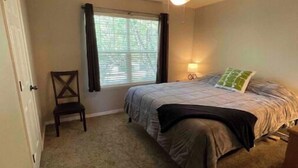 A bedroom with a bed, a chair, a ceiling fan, a window with curtains, and a nightstand with a lamp. - Clean, quiet, centrally located home (Salt Lake City)